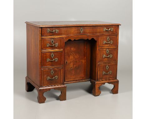 the top inset with gilt tooled green leather over a long drawer and six short drawers flanking a central cupboard, upon high 