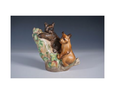 This charming Herend porcelain figurine, features a detailed depiction of two bears perched on a tree branch, surrounded by v