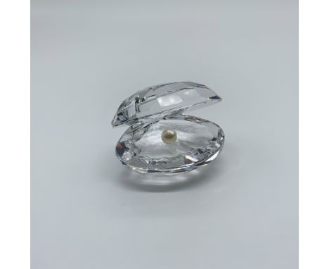 This Swarovski crystal figurine, designed by Michael Stamey, features a faceted clear crystal shell delicately holding a whit