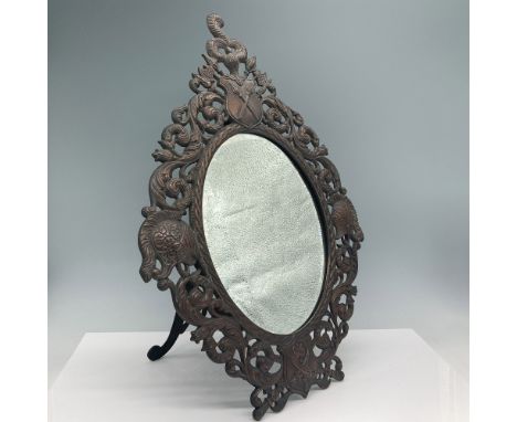 Exquisitely crafted cast iron vanity mirror featuring an ornate openwork frame with scrolling foliate details, heraldic shiel