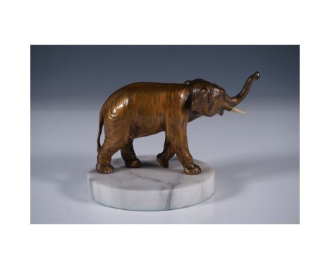 A finely crafted bronze elephant figurine with realistic detailing, mounted on a circular white marble base. The elephant is 