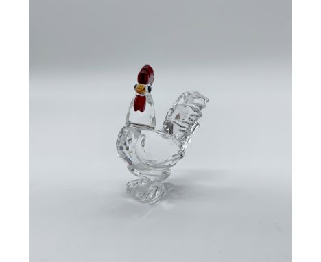 This Swarovski crystal figurine features a cockerel crafted primarily from clear crystal, accented with a siam (red) comb and