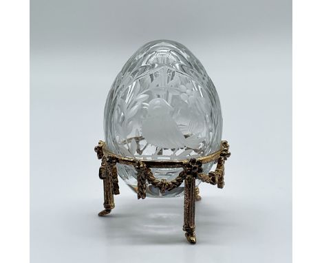 A finely crafted Fabergé crystal egg featuring intricate etched designs of a bird amidst foliage. The egg is signed Fabergé 0