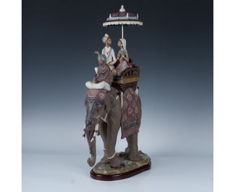 A stunning and large sculpture showcasing a beautifully adorned elephant carrying an Indian wedding couple, shaded by an umbr
