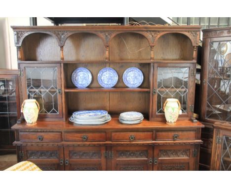 A modern carved light oak dresser, with two lead glazed doors, above four drawers an cupboard doors, on bracket feet, 183cm x