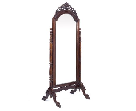 A WALNUT CHEVAL MIRROR the arching bevelled mirror plate within a frame with pierced scrolling crest, turned support and outs