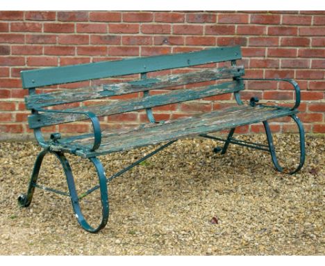 A GREEN PAINTED GARDEN BENCH with wrought iron ends and wooden slats, 161cm wide x 75cm high