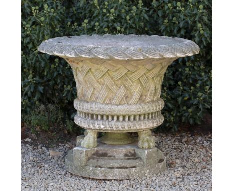 A LARGE COMPOSITE STONE PLANTER  with a flared rim, scalloped edge of woven basket design with four paw feet and mounted on a