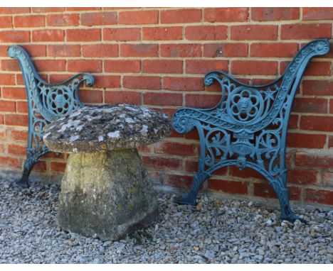 AN ANTIQUE COTSWOLD STADDLE STONE the top 55cm diameter x 46cm high together with a pair of cast metal bench ends (3)