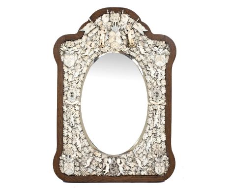 A 19TH CENTURY FRENCH DIEPPE IVORY MOUNTED WALL MIRROR with shaped oak frame and bevelled glass, surrounded by Cherubs and ov