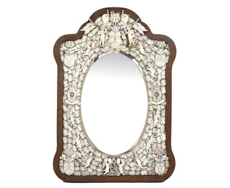 A 19TH CENTURY FRENCH DIEPPE IVORY MOUNTED WALL MIRROR with shaped oak frame and bevelled glass, surrounded by Cherubs and ov