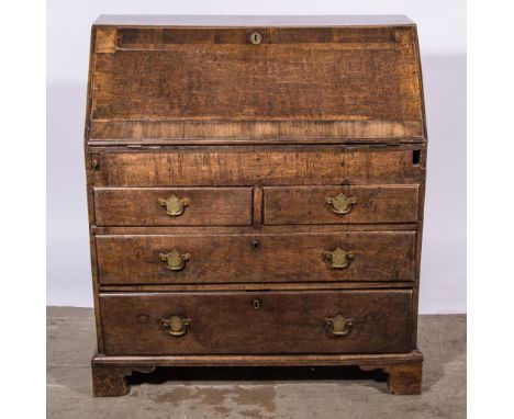 A George III oak bureau the fall-front crossbanded, well-fitted interior with drawers, pigeon holes and cupboard, two short a