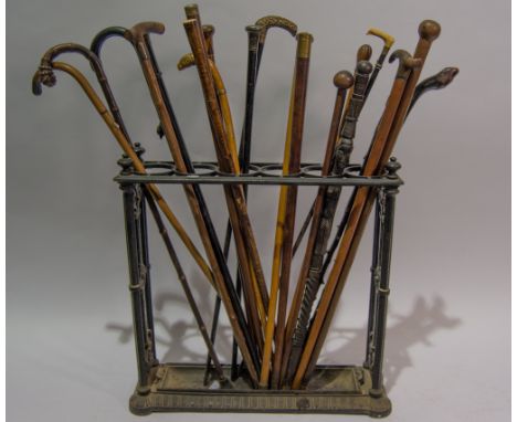 Victorian Coalbrookdale style cast iron stick stand, width 62cm, containing a collection of twenty-two walking sticks, some s