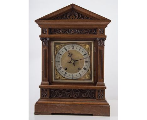 An oak mantel clock, architectural form, brass dial, the movement stamped W&H striking on two gongs, 44cms.