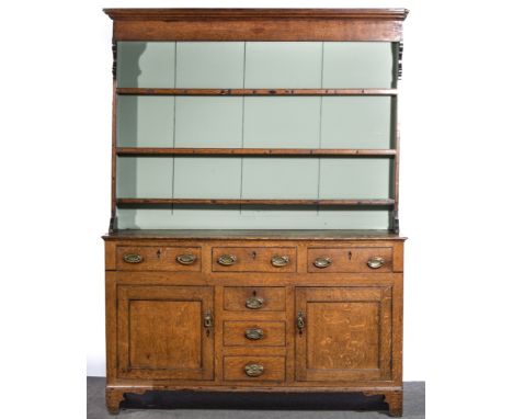 George III oak dresser, the panelled back with moulded cornice, three fixed shelves, the base with a rectangular top, four dr