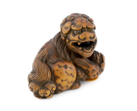 * A Japanese carved wood netsuke of a recumbent Shi-Shi, signed Toyomasa?, late 18th century, with horn inset eyes, 4cmProven