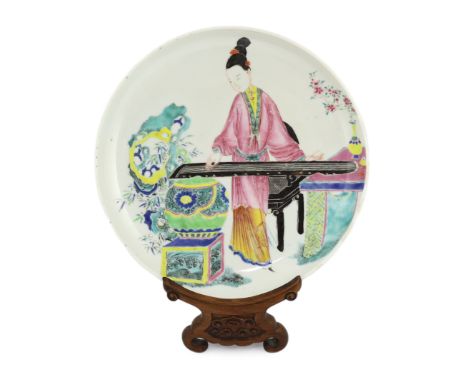 * A Chinese famille rose saucer dish, Yongzheng period, painted in enamels with a young woman playing a Qin, 25cm diameter, h