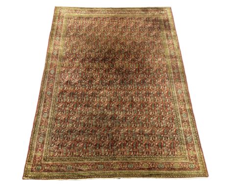 A Khorasan red ground carpet, woven with rows of boteh, approximately 12ft. X 9ft. (damage to one small area neatly repaired)