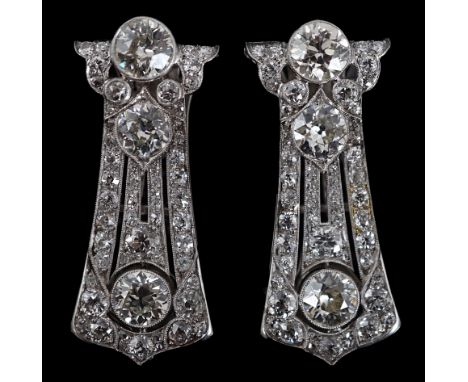A pair of Art Deco white gold and round cut millegrain set diamond cluster clip brooches, of tapering form, each set with thr
