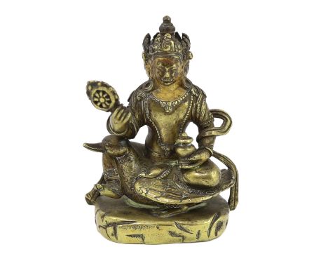 * * A Tibetan gilt bronze figure of a bodhisattva, 17th century, with four faces, holding a wheel and a vase, seated on a goo