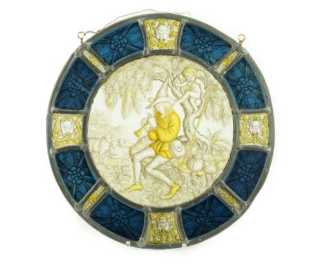 An 18th century Flemish stained glass panel, depicting a shepherd piper with Cupid behind, within a blue foliate panel border