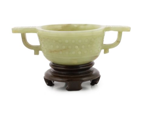 A Chinese celadon jade two handled cup, 17th century, decorated with a band of archaistic studs, with a pair of loop handles,
