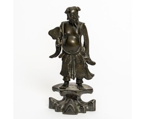 A CHINESE BRONZE STANDING FIGURE17th century Possibly depicting the Daoist immortal, Han Xiangxi, cast standing on a rocky pr
