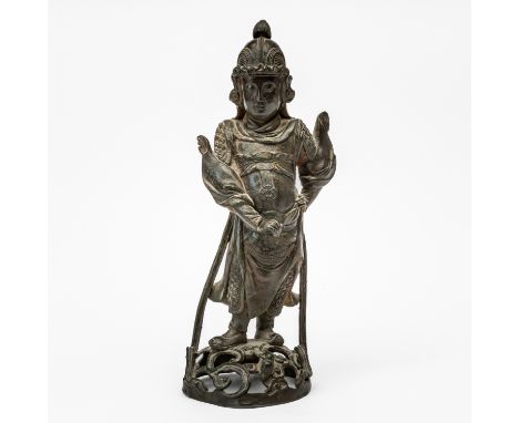 A CHINESE BRONZE FIGURE OF A GUARDIANMing dynasty Modelled standing with one hand on hip, wearing uniform and helmet, raised 