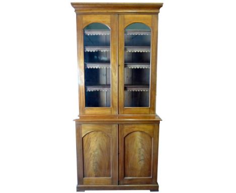 A Victorian mahogany bookcase, cornice over twin glazed doors enclosing four shelves with leather trimming, the base section 