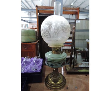 A brass oil lamp with ceramic well, etched glass shade and chimney
