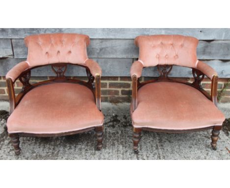 A pair of early 20th century low seat chairs, button upholstered in a pink fabric, on turned supports 