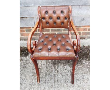 A polished as mahogany desk elbow chair of Regency design, button upholstered in a red leather 