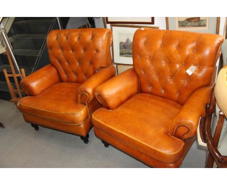 **A pair of brown leather button back armchairs, on turned supports (**Please note this lot is also subject to 20% VAT on the