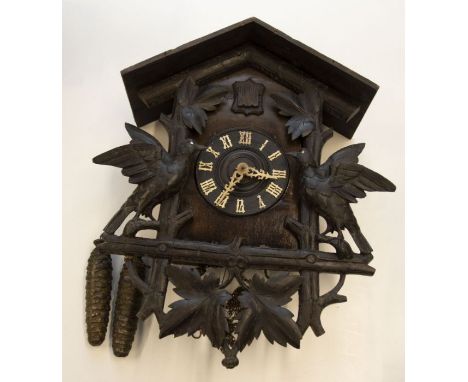 A Black Forest Cuckoo wall clock striking on a bell. Contained in a case with carvings of birds and leafs 6" dial. Brass 2 tr