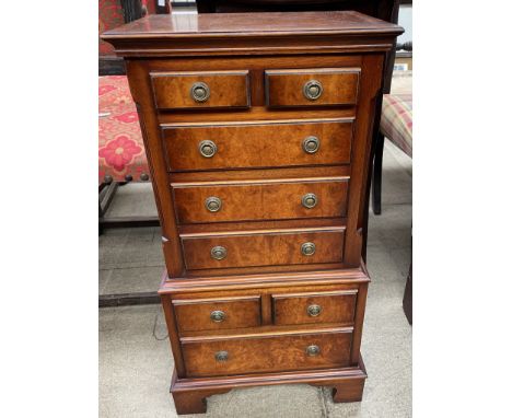 A reproduction walnut miniature chest on chest, with a rectangular crossbanded top above eight drawers on a bracket feet