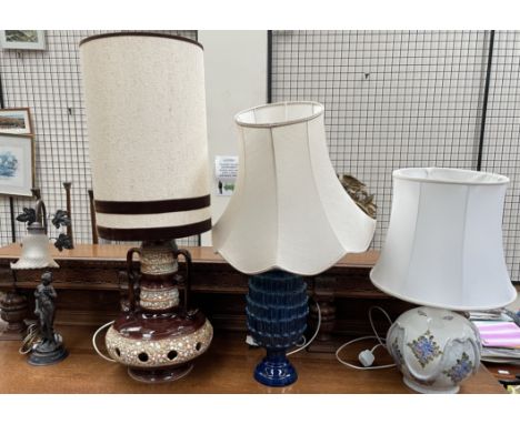 A mid 20th century pottery table lamp with cream and brown body and a tall shade together with two other pottery table lamps 