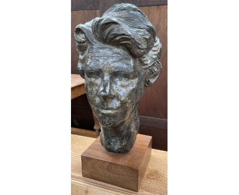 A bronzed portrait bust of a lady's head on a square plinth