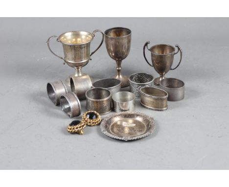 Nine assorted silver napkin rings, three silver trophies, a silver dish and a pair of gilt metal ear clips 