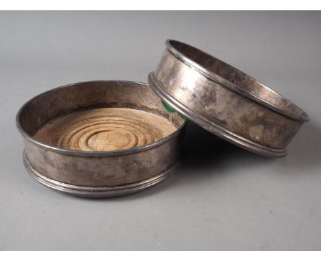 A pair of silver wine bottle coasters with turned wooden bases, 5" dia 