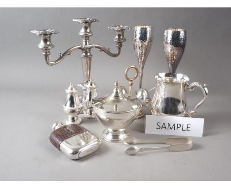A pair of silver plated champagne flutes with hammered design, two plated mugs, a candelabra, a hanging cheese knife set, two