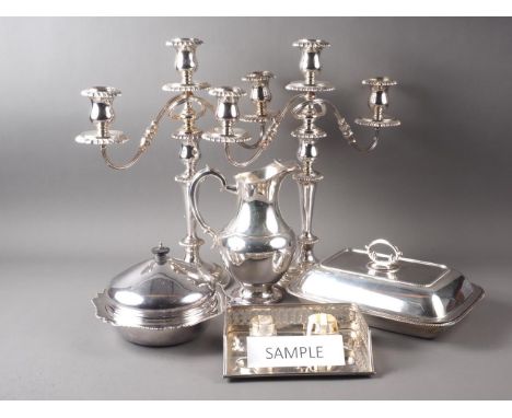 A pair of silver plated three-light table candelabra, a pair of single light candlesticks, a plated and embossed cake basket,