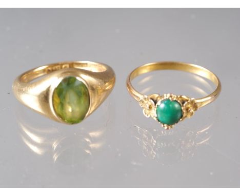 An 18ct gold and peridot single stone ring, size I, 6.9g, and a yellow metal and jade cabochon ring, size M, 1.2g 