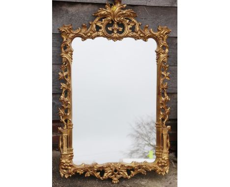 A carved giltwood framed wall mirror of Chippendale design with scroll crest, 42" x 25" overall 
