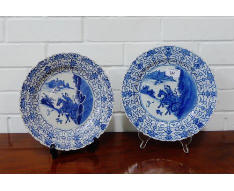 A pair of Chinese blue and white foliate rim 'Hunting' pattern dishes, each with a six character mark to the base and double 