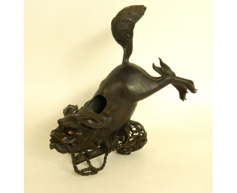 CHINESE BRONZE DOG OF FO ZUN
jumping over a pierced decorated ball with its rear legs raised, now lacking the hinged cover to