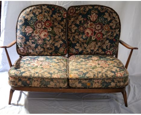 ERCOL TWO SEAT SOFA
with a shaped stick back and loose floral back and seat cushions, standing on turned tapering supports, 1