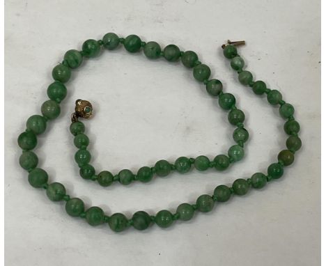 A necklace of graduated jade beads with 9ct clasp set with jade cabochons. 15" long.