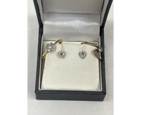A 9ct diamond cross-over ring; an 18ct diamond cluster ring and a pair of silver and diamond heart shaped earrings. The rings
