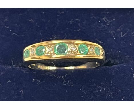 A nine stone emerald and diamond ring. In gold marked 375. 1g gross, size N.