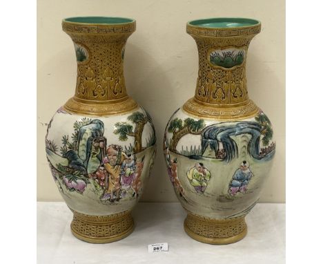 A pair of 20th Century Chinese vases, with carved necks, decorated with a continuous garden scene with figures in low relief.